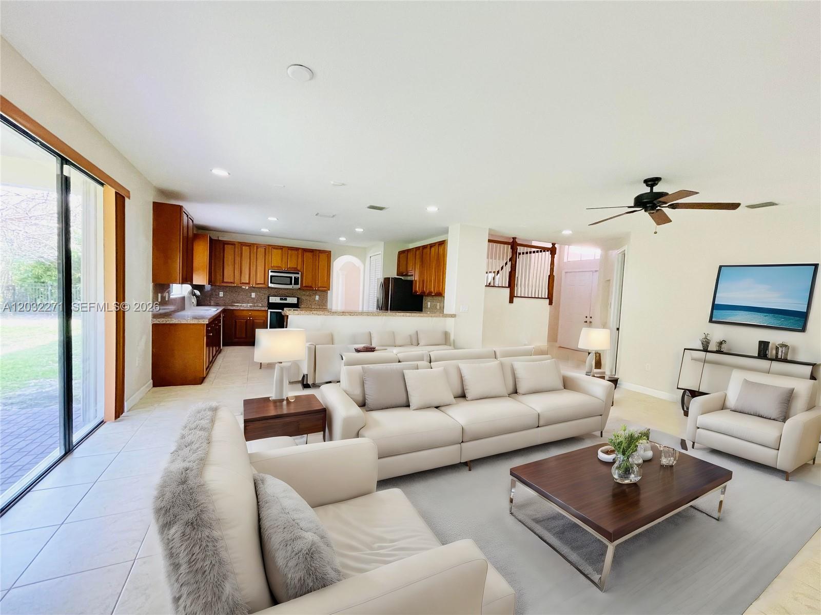 An open-concept living room features light-colored sofas, a dark wood coffee table, and a kitchen — 7427 SW 189th St, Cutler Bay FL 33157, CUTLER BAY, FL