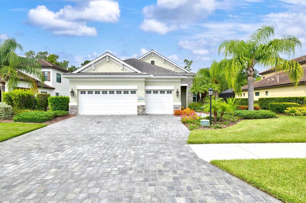 A single-story house with a paved driveway, two-car garage, and palm trees in the front yard — 21221 WACISSA DRIVE, VENICE, FL