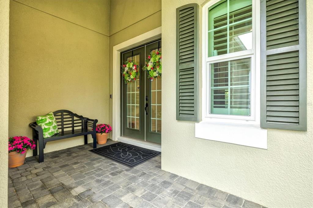 A covered front porch features a black bench, potted flowers, and a double-door entrance — 21221 WACISSA DRIVE, VENICE, FL