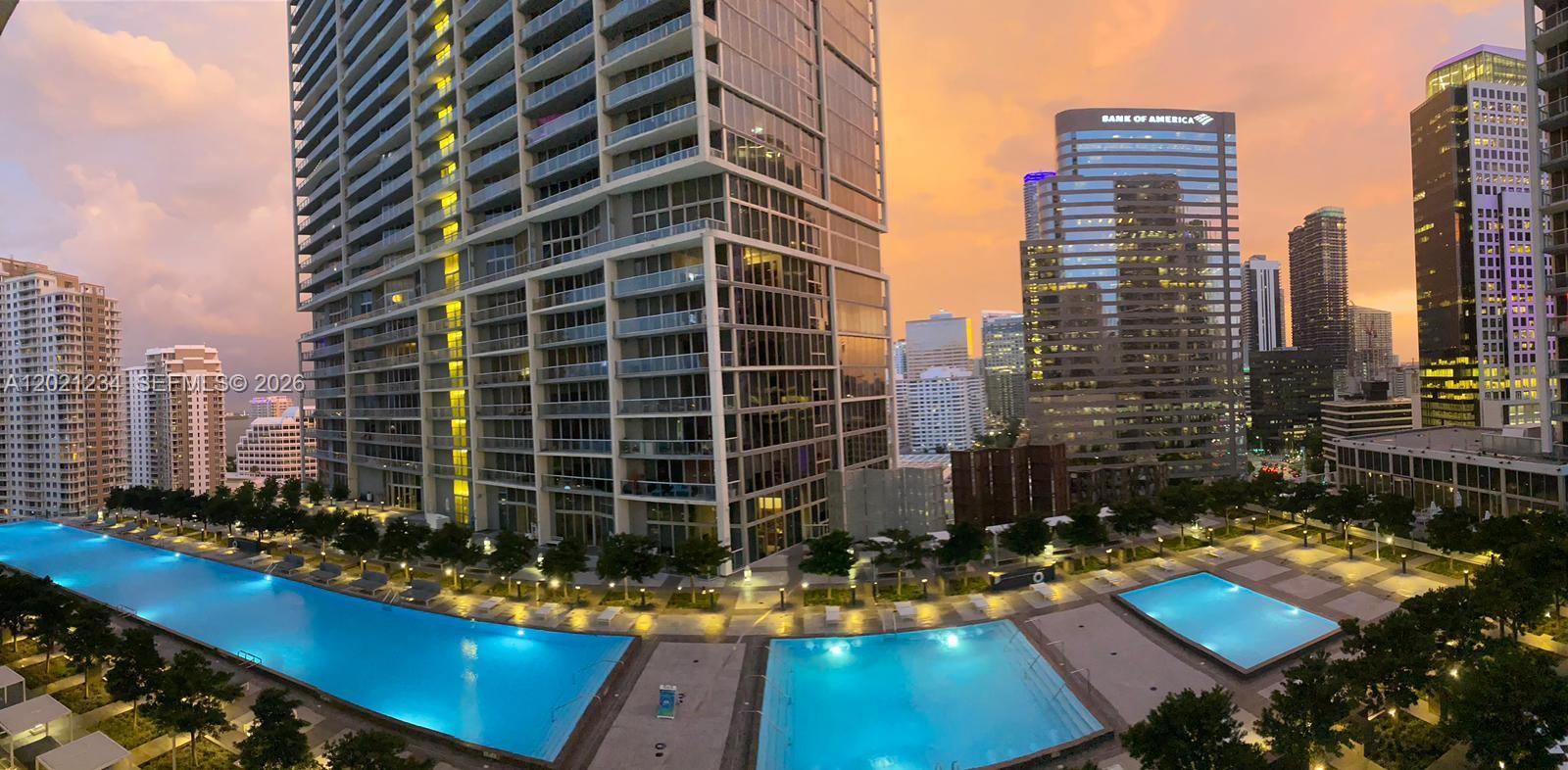 An elevated view of a luxury apartment complex with multiple swimming pools at sunset — 475 Brickell Ave # 1813, Miami FL 33131, MIAMI, FL