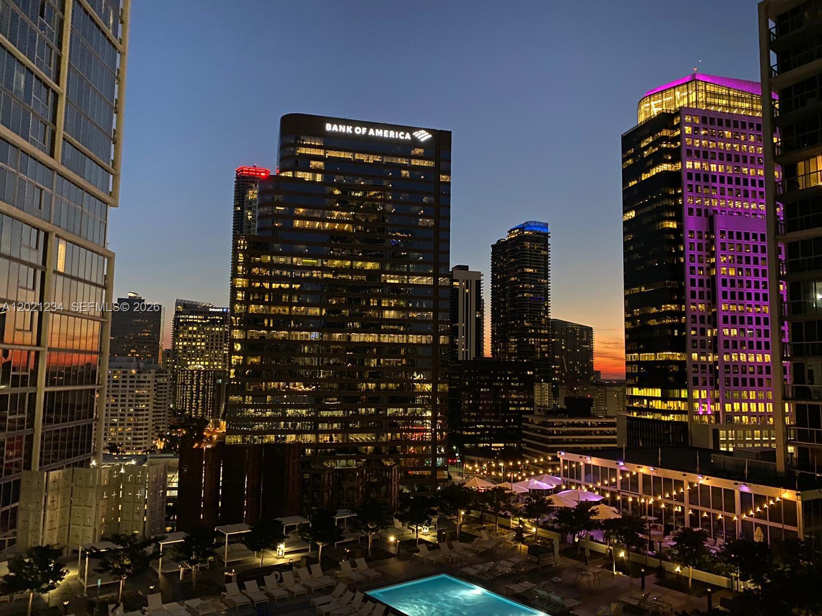 A high-angle view of a city skyline at dusk featuring a pool deck below — 475 Brickell Ave # 1813, Miami FL 33131, MIAMI, FL