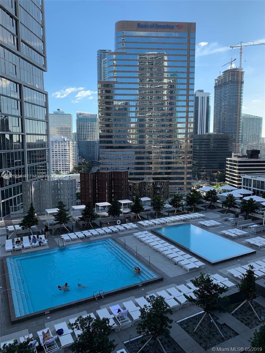 An elevated view of a swimming pool deck with lounge chairs overlooking a city skyline — 475 Brickell Ave # 1813, Miami FL 33131, MIAMI, FL