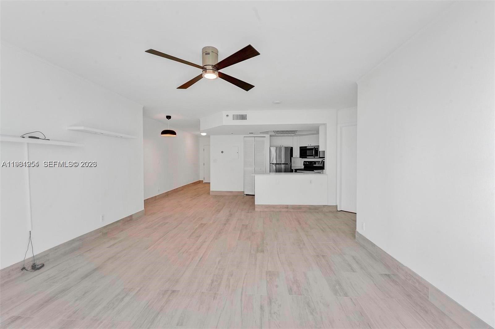 An open-concept living area features light wood-look flooring, white walls, and a ceiling fan — 8911 Collins Ave # 703, Surfside FL 33154, SURFSIDE, FL