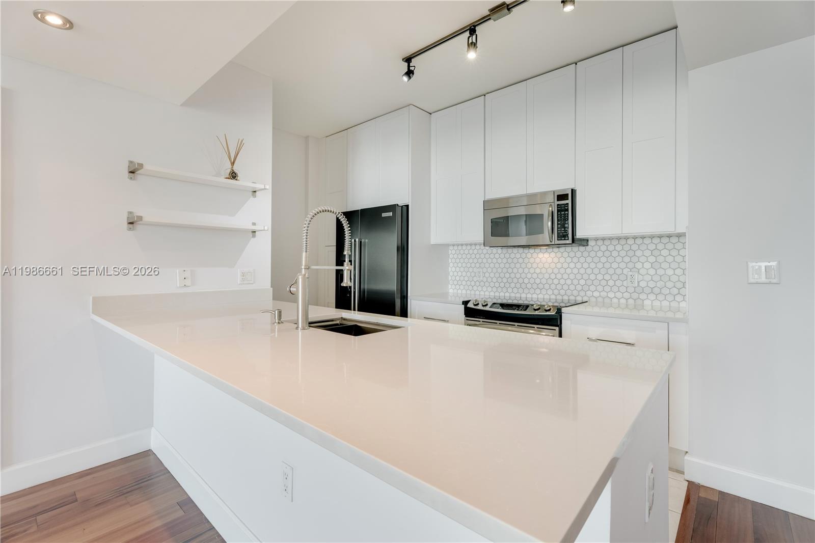 A modern kitchen features white cabinetry, a quartz island, and a stainless steel microwave — 951 Brickell Ave # 3607, Miami FL 33131, MIAMI, FL