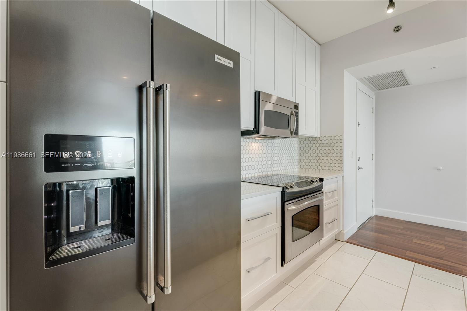A modern kitchen features stainless steel appliances, white cabinetry, and a hexagonal tile backsplash — 951 Brickell Ave # 3607, Miami FL 33131, MIAMI, FL