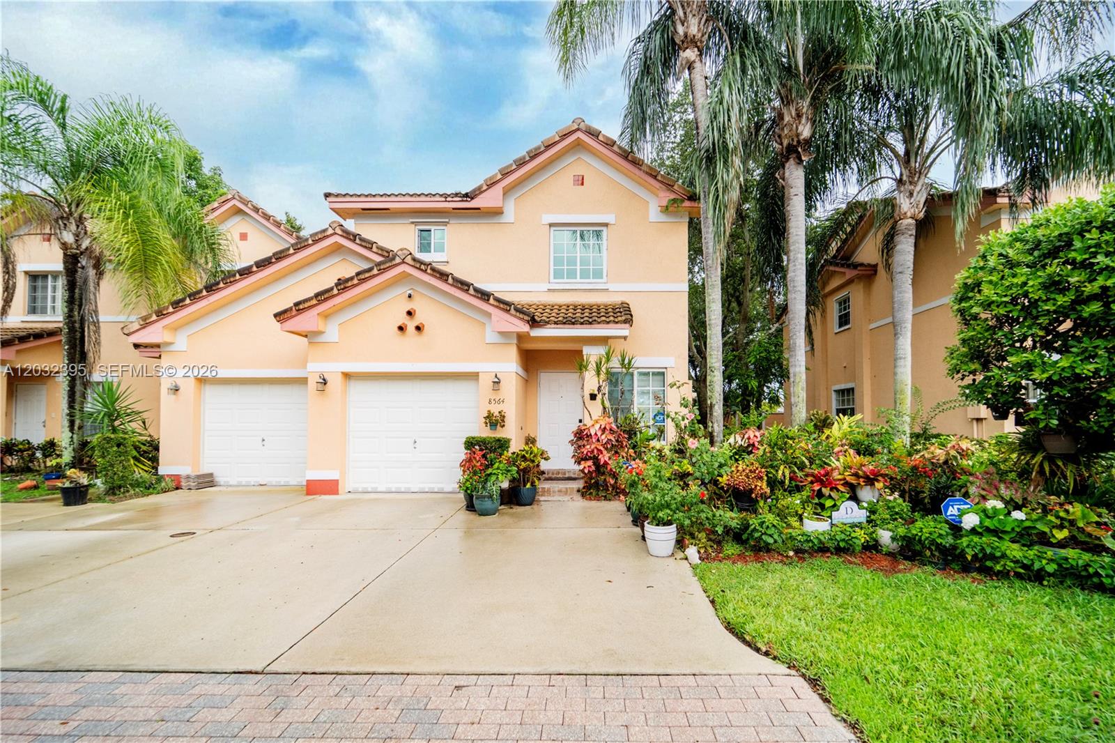 A two-story peach-colored house features a two-car garage, a front entrance, and lush landscaping — 8564 SW 23rd Ct, Miramar FL 33025, MIRAMAR, FL