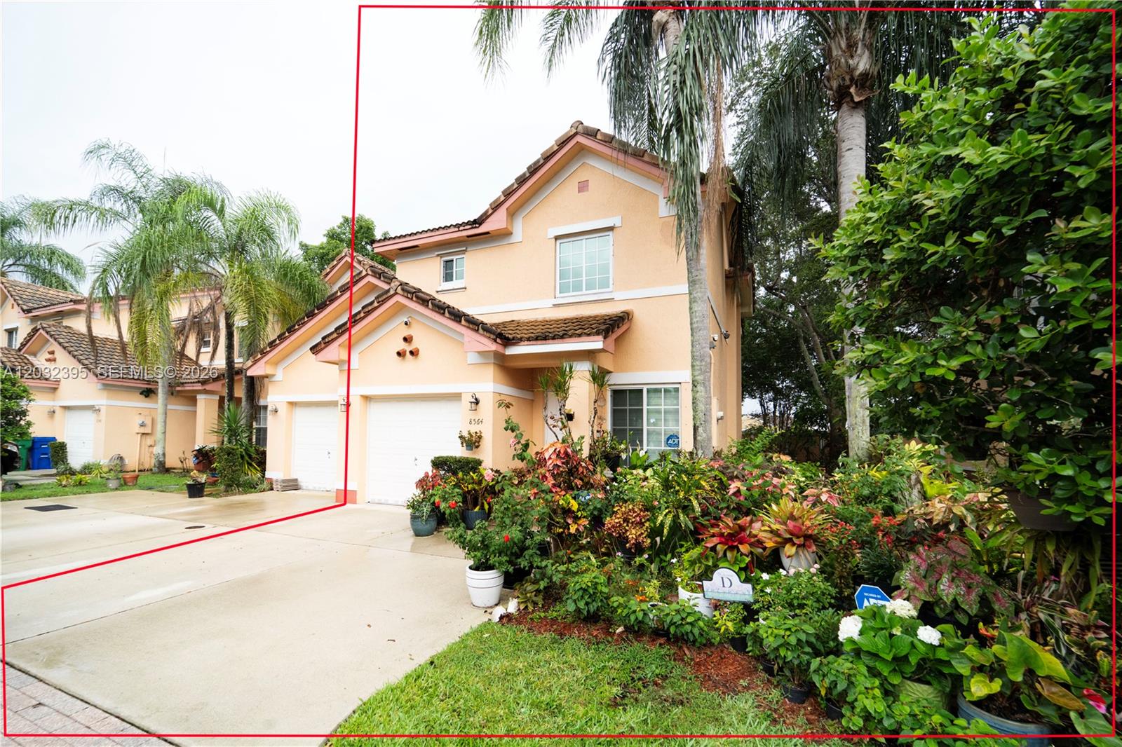 A two-story peach-colored house features a two-car garage and a lush front garden — 8564 SW 23rd Ct, Miramar FL 33025, MIRAMAR, FL