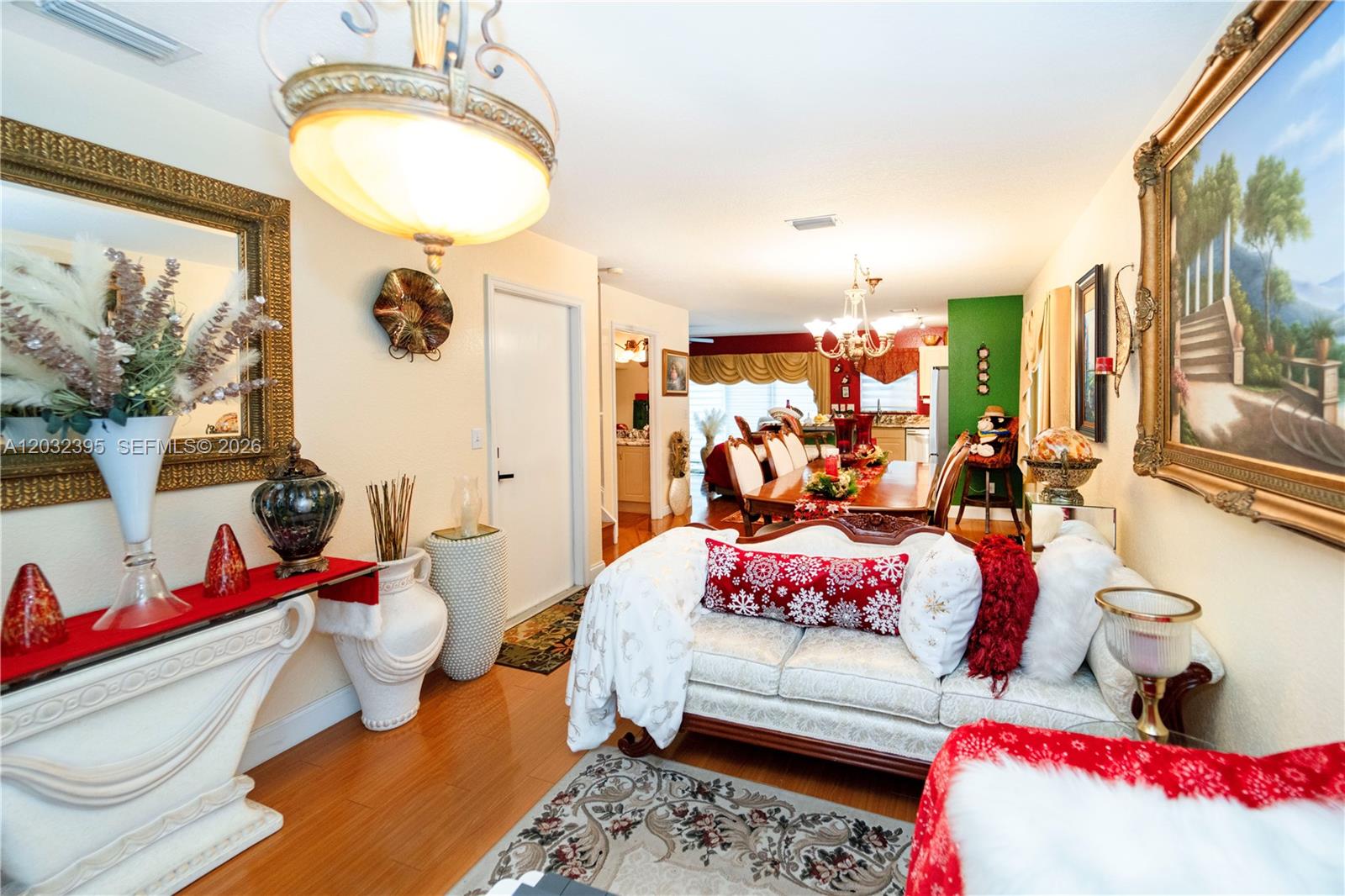 A living room with a white sofa, hardwood floors, and a dining area in the background — 8564 SW 23rd Ct, Miramar FL 33025, MIRAMAR, FL