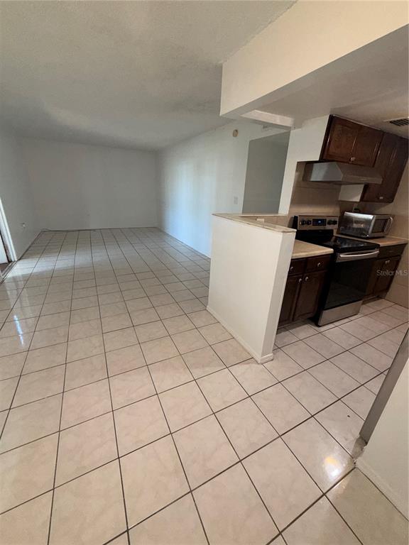 A kitchen with dark wood cabinets and stainless steel appliances opens to a tiled room — 1432 HOLDEN AVENUE UNIT C6, ORLANDO, FL