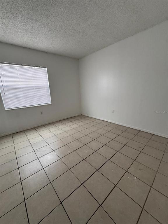 An empty room features white walls, a single window with blinds, and light-colored tile flooring — 1432 HOLDEN AVENUE UNIT C6, ORLANDO, FL