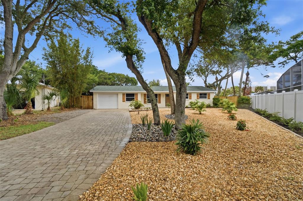 A single-story house with a paved driveway, gravel front yard, and mature trees — 1 CARLEY CIRCLE, NEW SMYRNA BEACH, FL