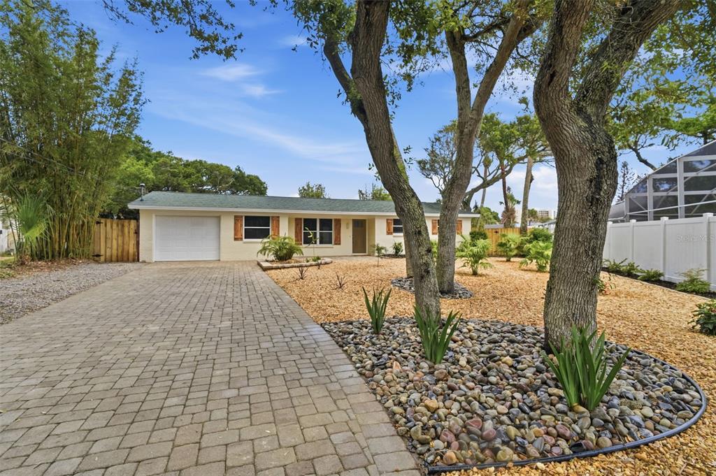 A single-story house with a paved driveway, gravel landscaping, and mature trees in the yard — 1 CARLEY CIRCLE, NEW SMYRNA BEACH, FL