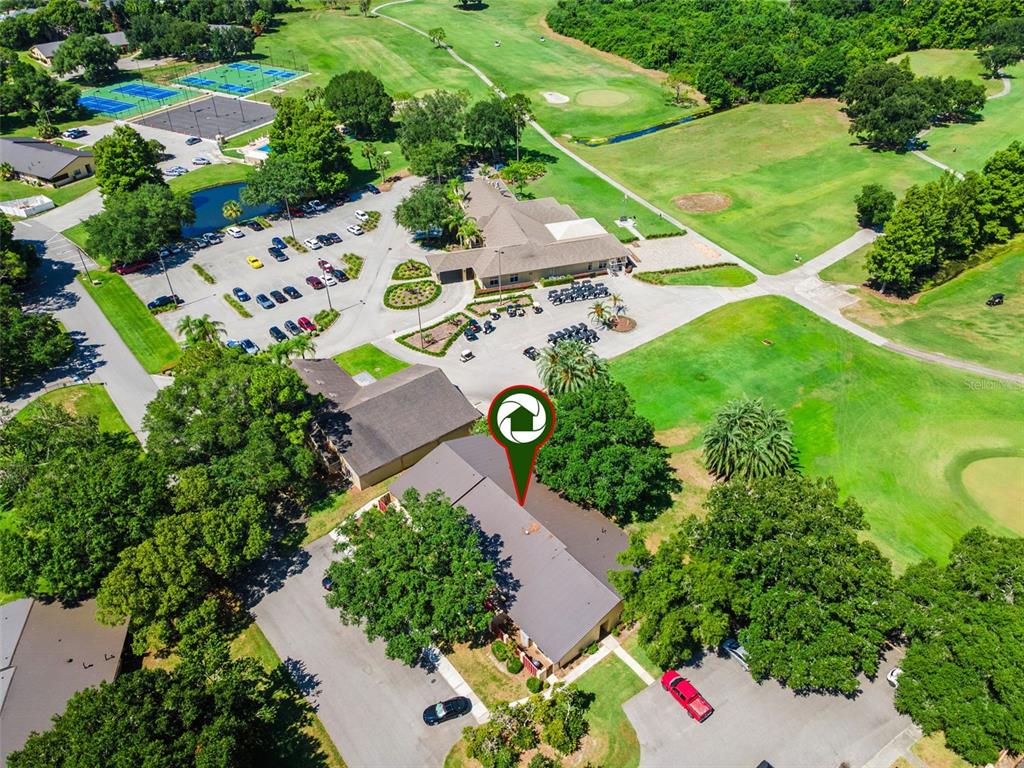An aerial view shows a multi-unit residential building with a parking lot and golf course — 664 CLUBHOUSE ROAD, WINTER HAVEN, FL