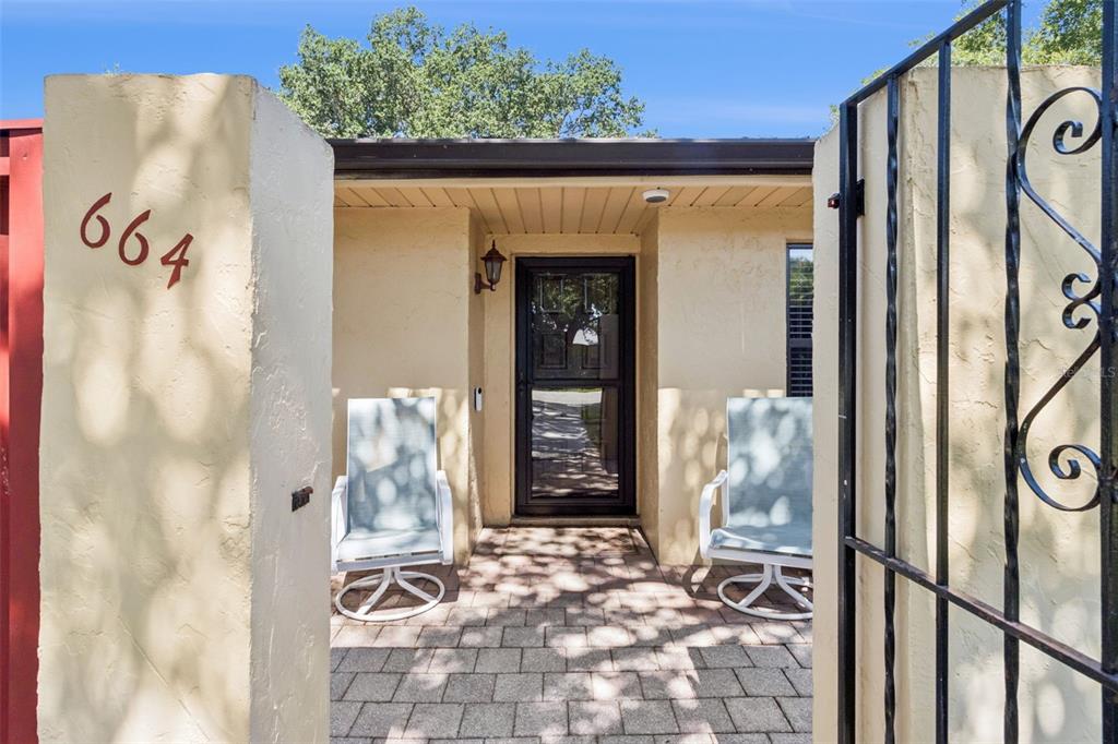 A paved entryway features two chairs, a glass storm door, and a stucco wall — 664 CLUBHOUSE ROAD, WINTER HAVEN, FL