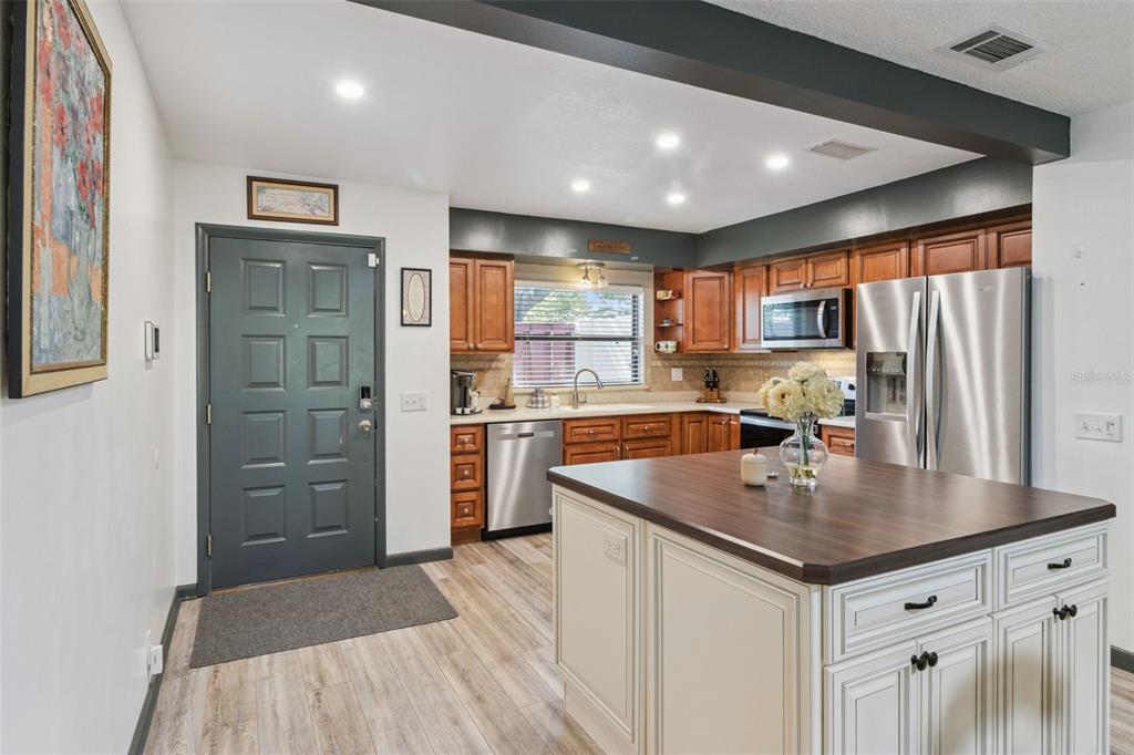 A kitchen features wood cabinets, stainless steel appliances, a center island, and a dark door — 664 CLUBHOUSE ROAD, WINTER HAVEN, FL