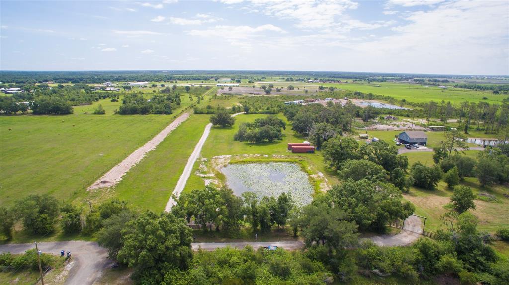 An aerial view shows a rural property with a pond, a gravel driveway, and trees — 7977 BARR ROAD, MYAKKA CITY, FL