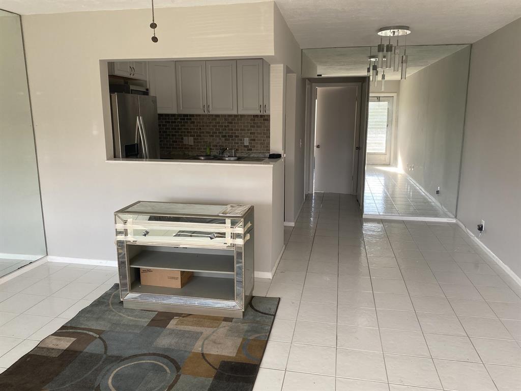 A kitchen with white cabinets and a mirrored console table sits on a tiled floor — 71 Easthampton # C, West Palm Beach FL 33417, WEST PALM BEACH, FL