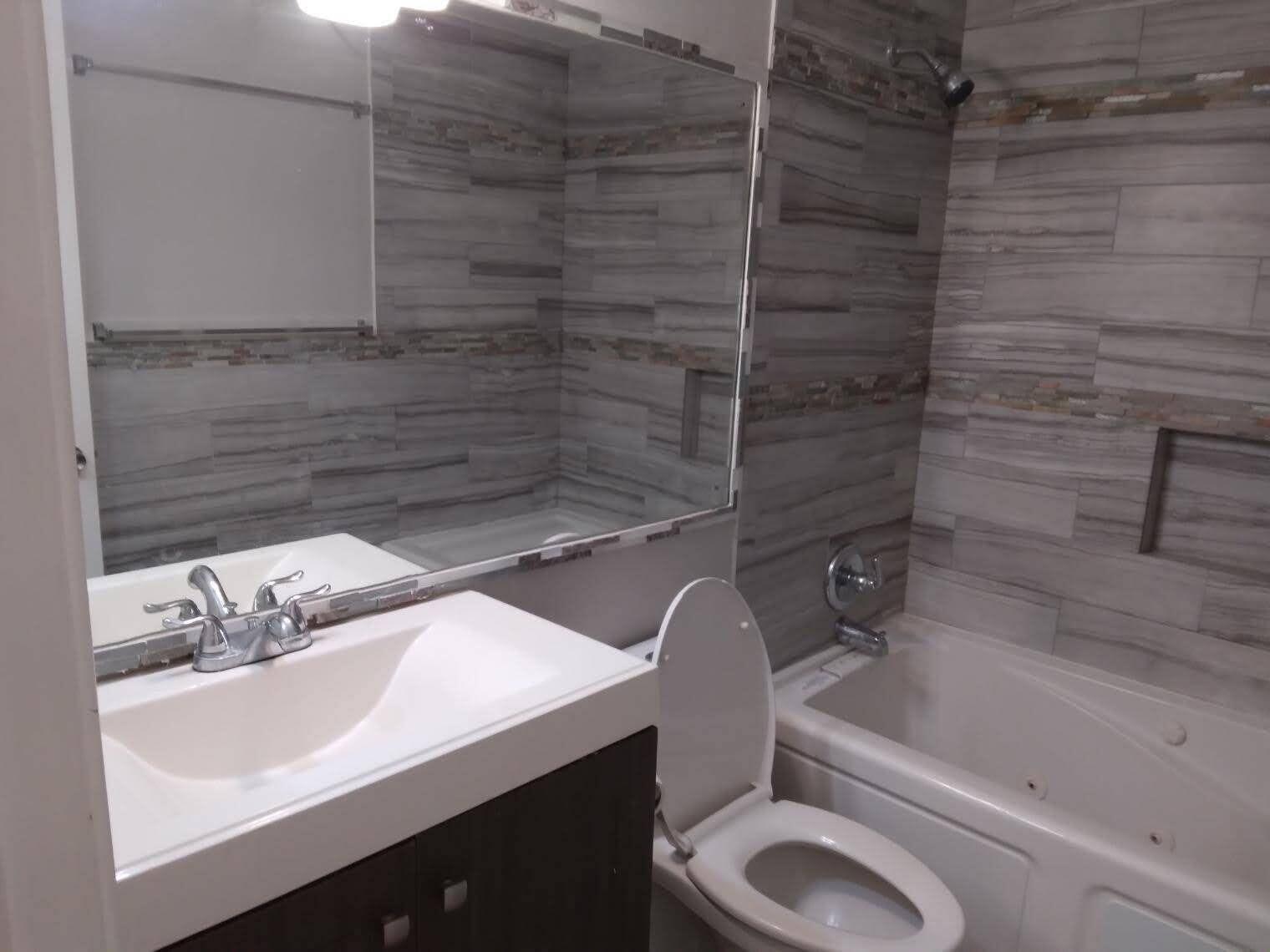 A bathroom features a vanity with a sink, a toilet, and a tiled bathtub shower — 71 Easthampton # C, West Palm Beach FL 33417, WEST PALM BEACH, FL