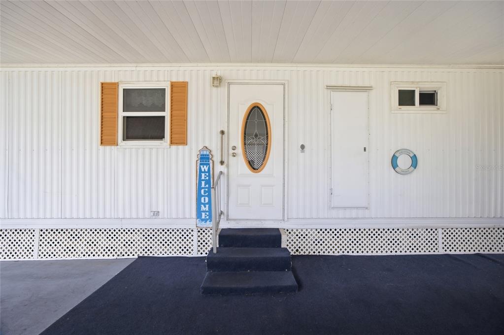 The exterior of a mobile home features a white door, a window, and blue steps — 9900 ULMERTON ROAD UNIT 242, LARGO, FL