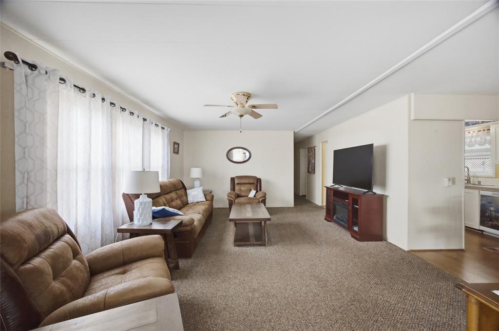 A living room features brown carpet, tan walls, a ceiling fan, and brown furniture — 9900 ULMERTON ROAD UNIT 242, LARGO, FL