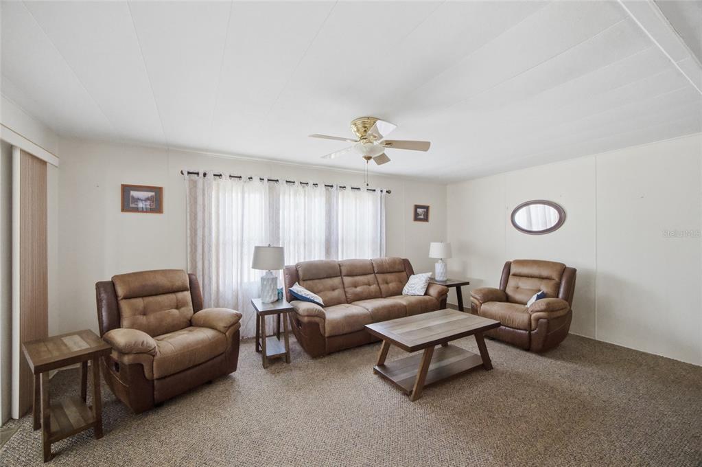 A living room features a brown sofa, two matching recliners, and a wooden coffee table — 9900 ULMERTON ROAD UNIT 242, LARGO, FL