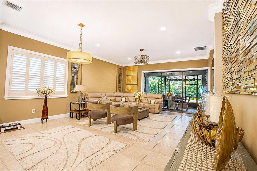 A living room features beige walls, tile flooring, a sectional sofa, and a textured accent wall — 13139 BROMBOROUGH DRIVE, ORLANDO, FL