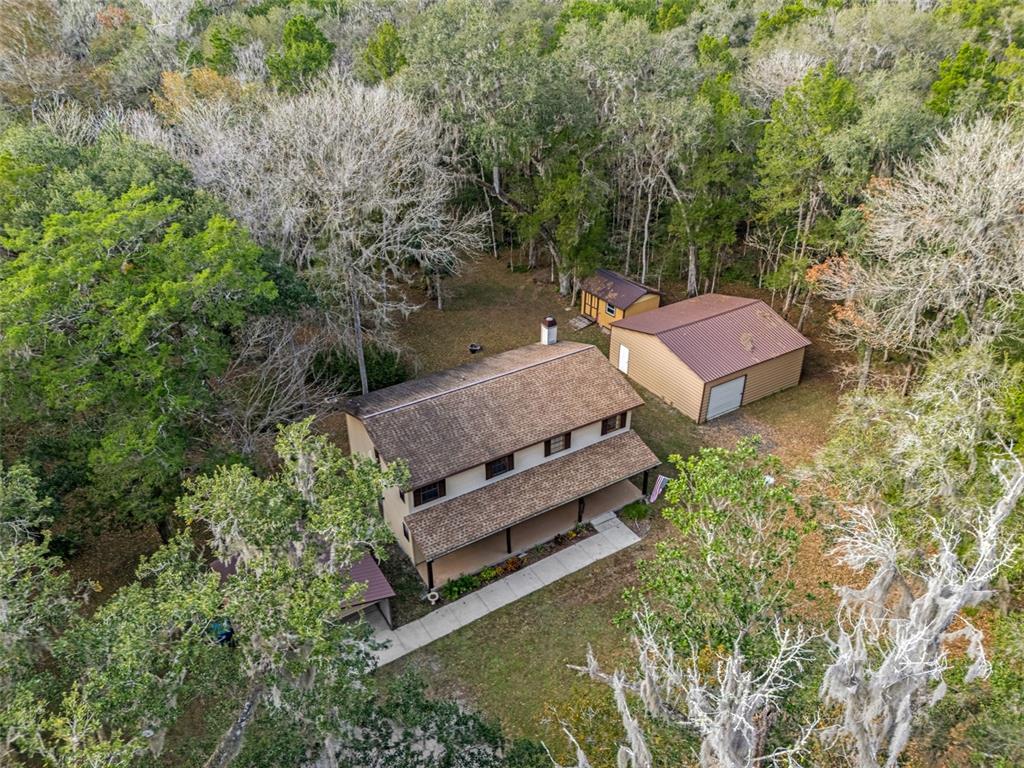An aerial view shows a two-story house with a metal-roofed garage and shed nearby — 12047 TIMBER LANE, BROOKSVILLE, FL