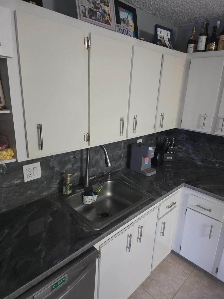 A kitchen features white cabinets, dark marble-look countertops, and a stainless steel sink — 2164 White Pine Circle # B, FL 33415, FL