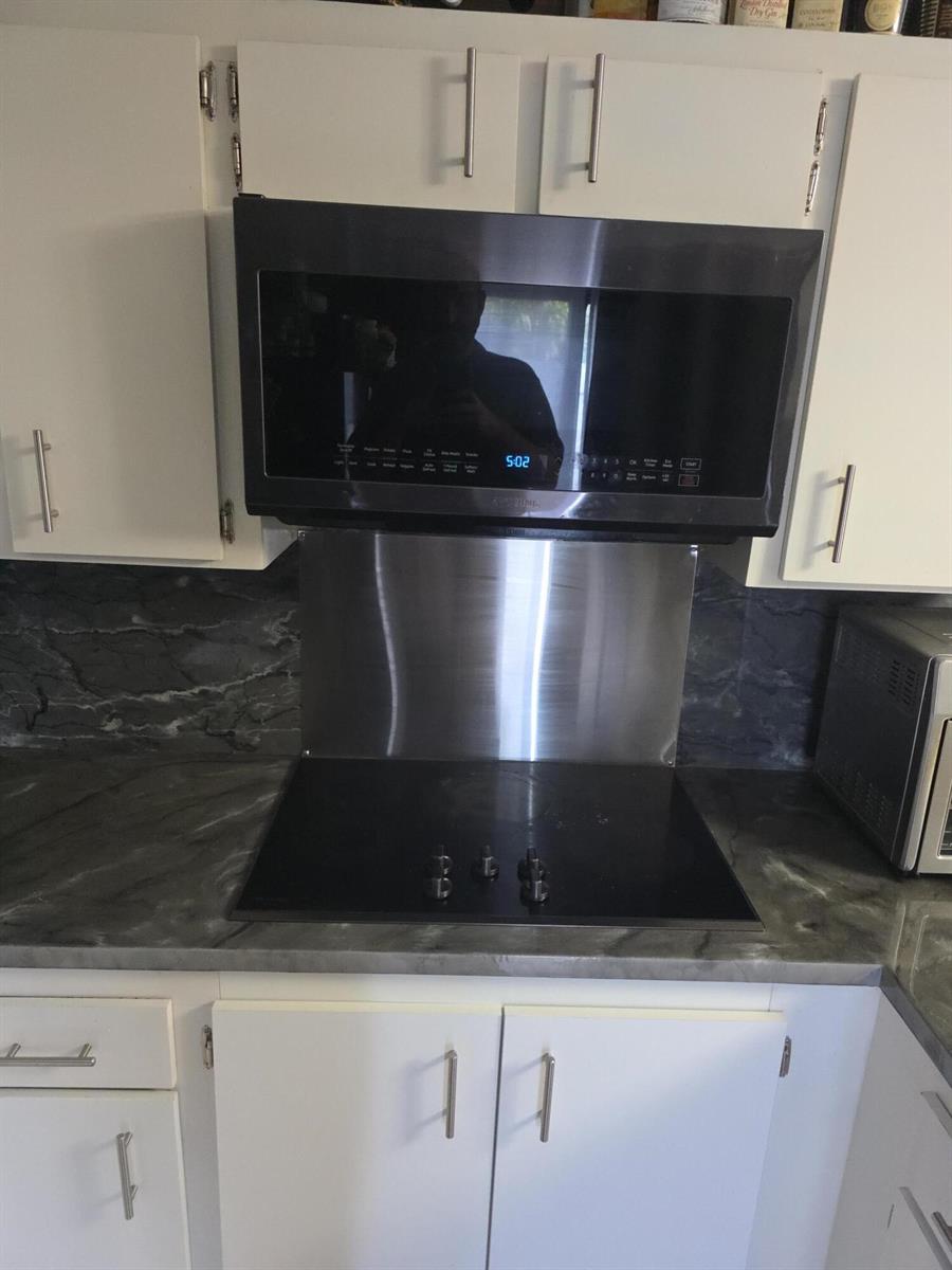 A kitchen features a black over-the-range microwave, a glass cooktop, and dark marble-patterned countertops — 2164 White Pine Circle # B, FL 33415, FL