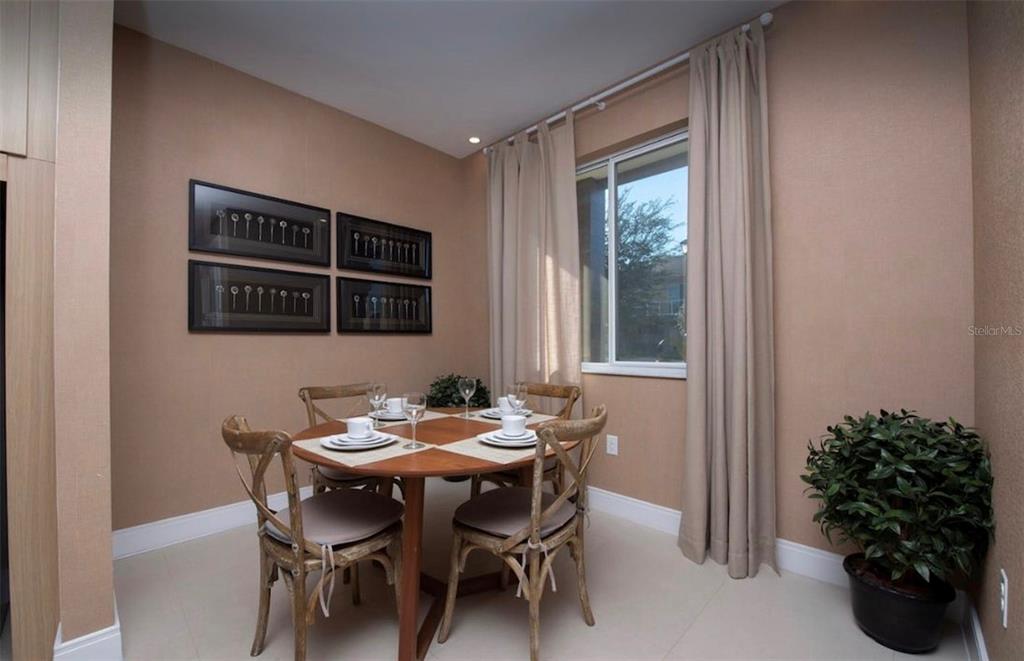 A dining area features a round wooden table with four chairs and framed wall art — 3229 BRASILIA AVENUE, KISSIMMEE, FL