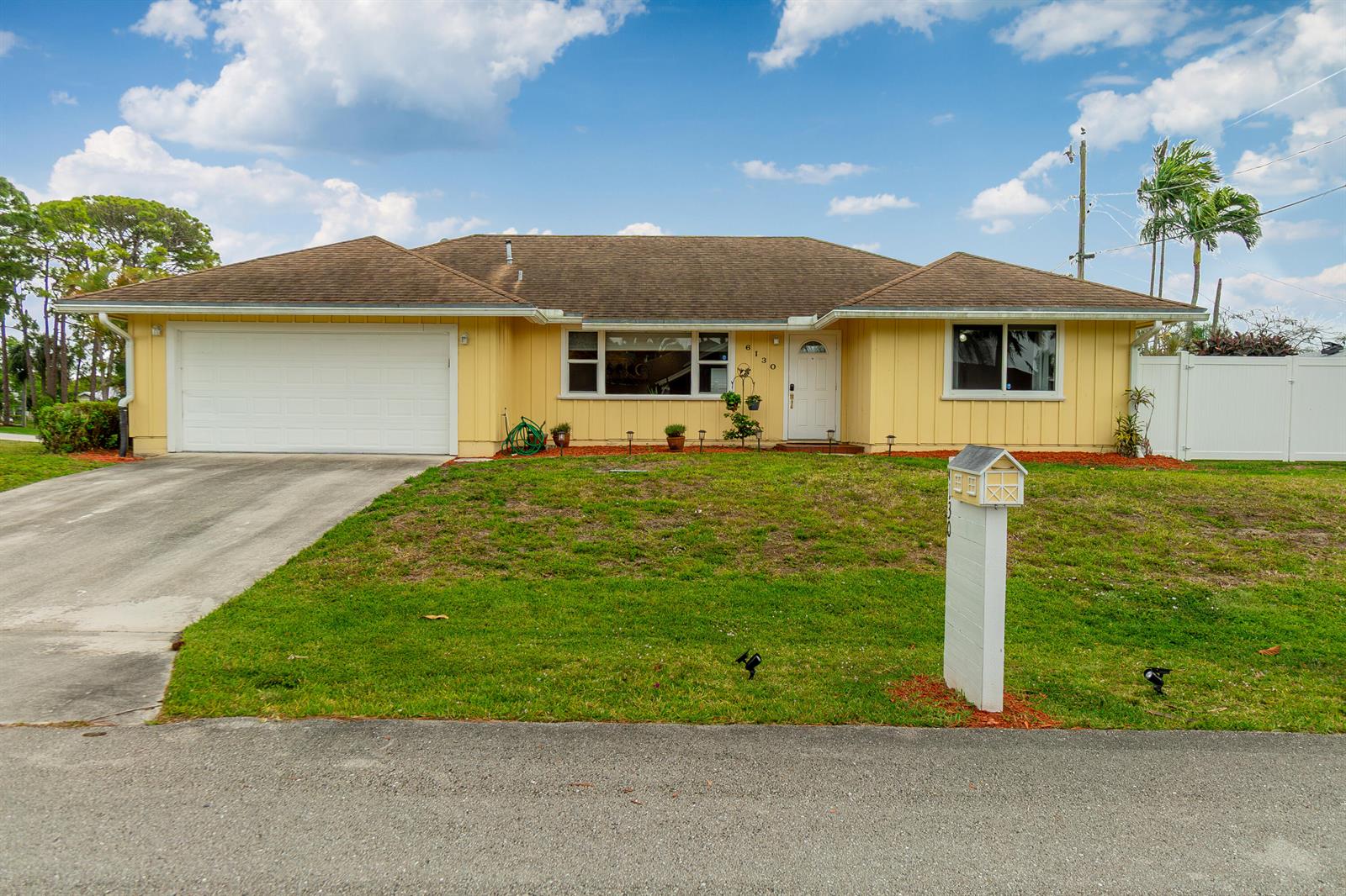 A yellow single-story house with a white garage door, a concrete driveway, and a mailbox — 6130 Francis Street, Jupiter FL 33458, JUPITER, FL