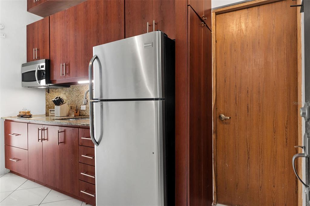 A kitchen features dark wood cabinets, stainless steel appliances, and a wooden door — 307 SAN SEBASTIAN UNIT 2-B, SAN JUAN, PR