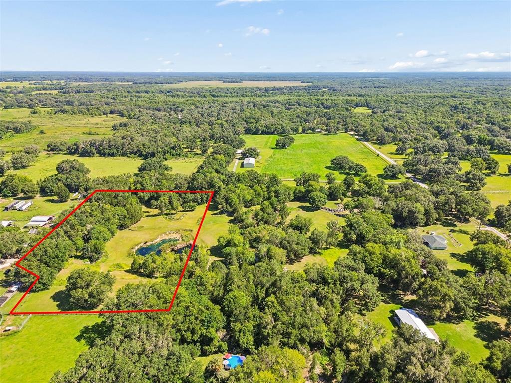 An aerial view shows a rural property with a pond outlined in red — 8800 S STEED TERRACE, FLORAL CITY, FL