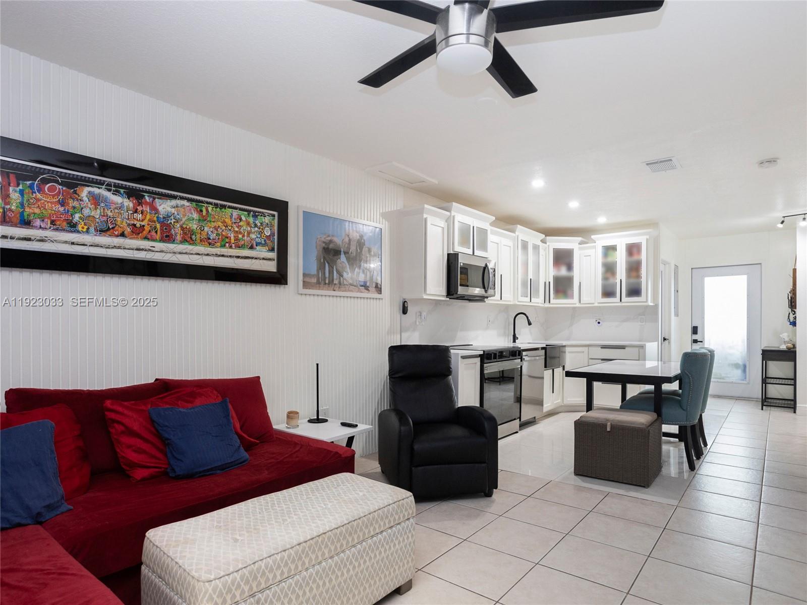 This open-concept living area features a red sofa, a black recliner, and a white kitchen — 437 SW 3rd St # 2, Miami FL 33130, MIAMI, FL