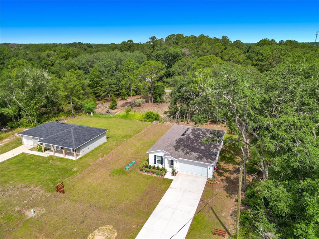 An aerial view shows two single-story houses with driveways surrounded by a wooded landscape — 50 BAY ROAD, OCKLAWAHA, FL