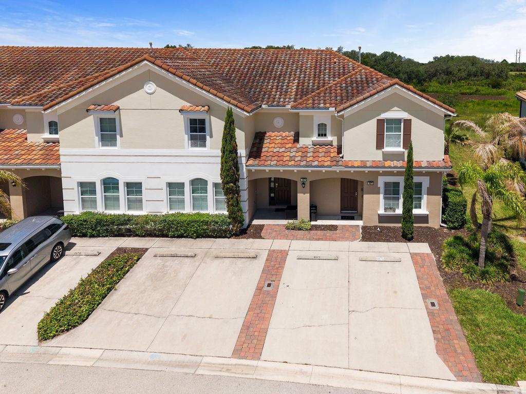 An aerial view of a two-story townhouse with a tiled roof and private parking spaces — 4671 TERRASONESTA DRIVE, DAVENPORT, FL