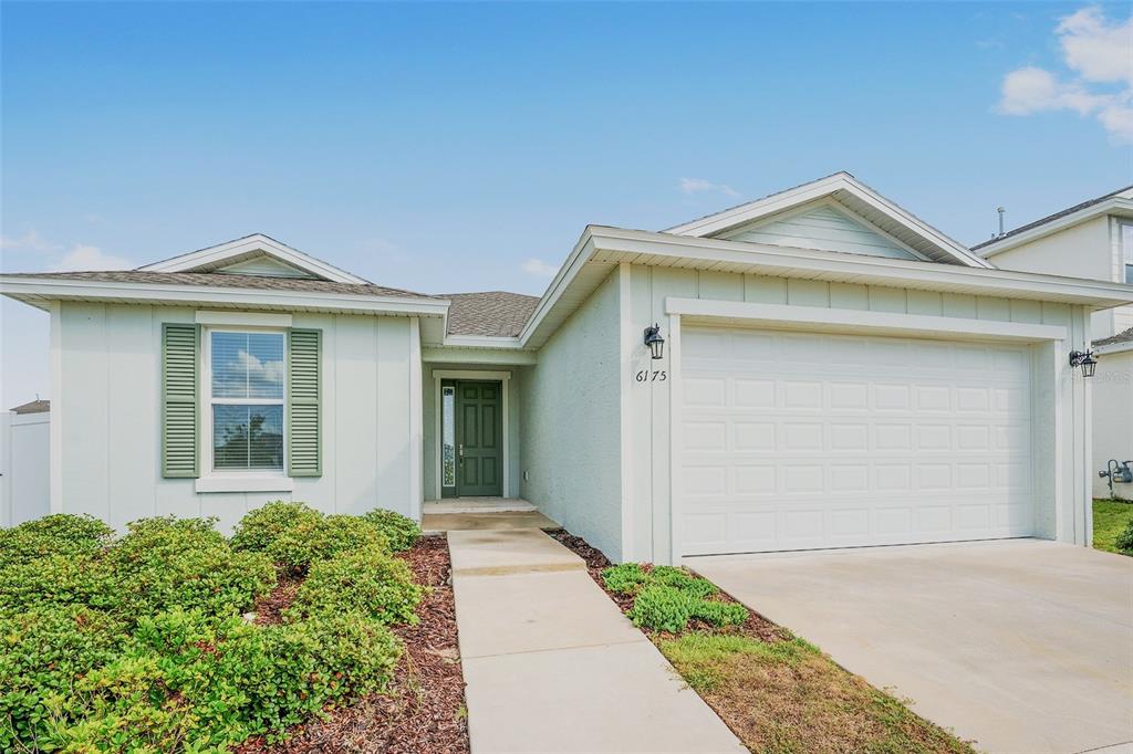 A light green single-story house features a two-car garage and a front walkway — 6175 SW 74TH COURT, OCALA, FL