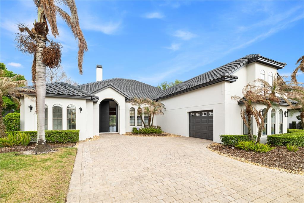 A single-story house with a white stucco exterior, dark tiled roof, and a paved driveway — 812 JOHNS POINT DRIVE, OAKLAND, FL