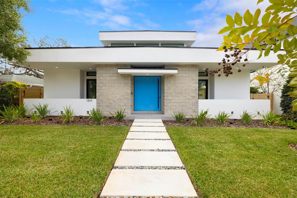 A modern single-story house features a bright blue front door and a stone facade — 1304 W FRIBLEY STREET, TAMPA, FL