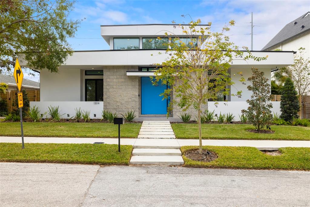 A modern single-story house features a bright blue front door and a stone facade — 1304 W FRIBLEY STREET, TAMPA, FL