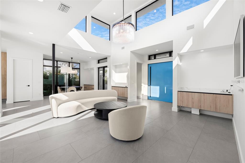 A bright living room features a curved white sofa, a blue door, and high ceilings — 1304 W FRIBLEY STREET, TAMPA, FL