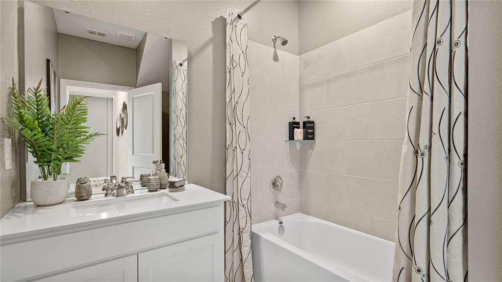 A bathroom features a white vanity with a sink, a bathtub, and a shower curtain — 3138 MINDFULLNESS DRIVE, CLERMONT, FL