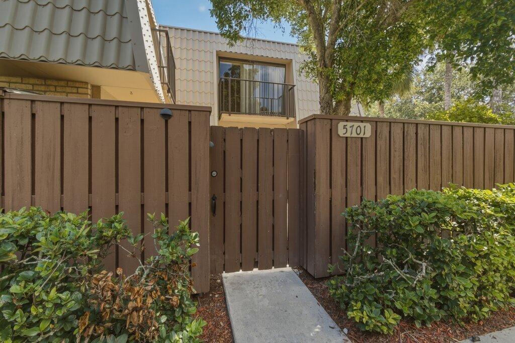 A wooden fence with a gate leads to the entrance of a two-story residential building — 5701 57th Way, West Palm Beach FL 33409, WEST PALM BEACH, FL