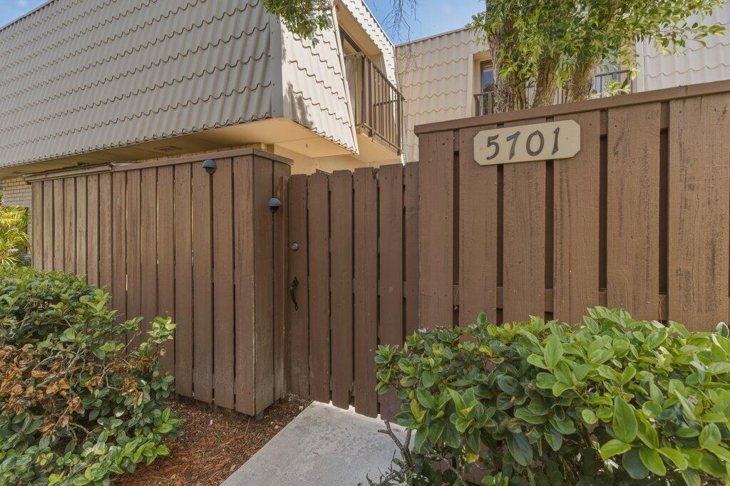 A wooden fence with a gate and house number 5701 stands before a two-story building — 5701 57th Way, West Palm Beach FL 33409, WEST PALM BEACH, FL
