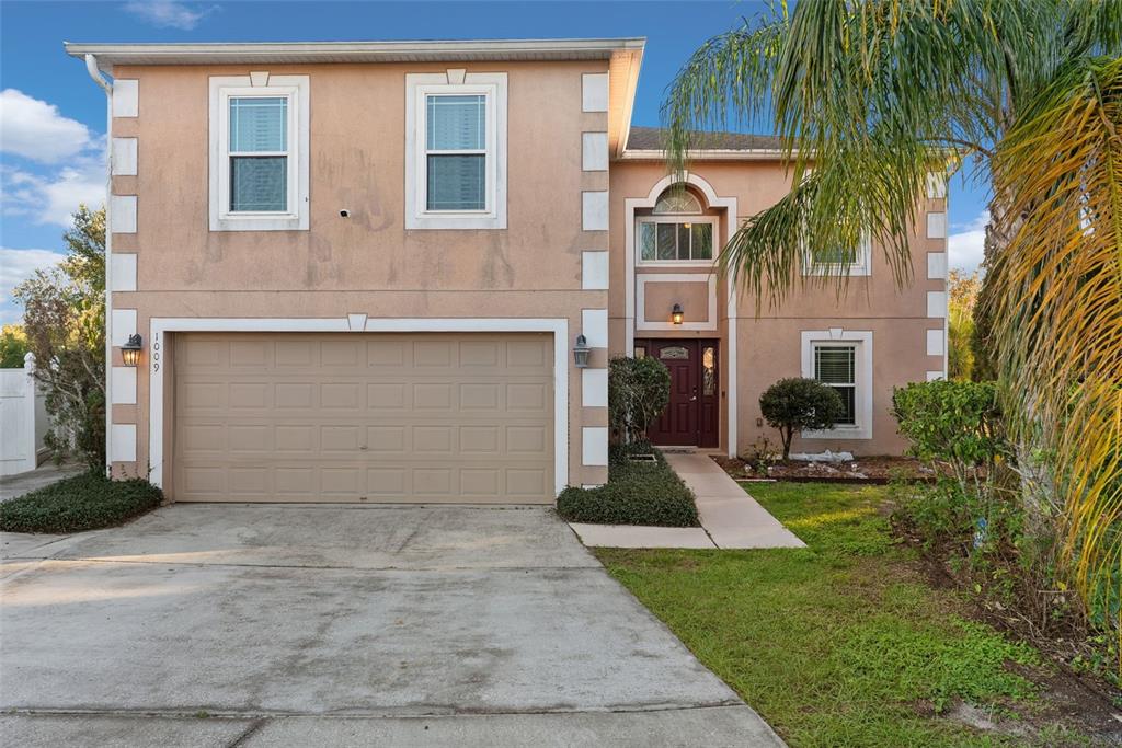 A two-story house with a tan stucco exterior, white corner accents, and a two-car garage — 1009 RONLIN STREET, HAINES CITY, FL