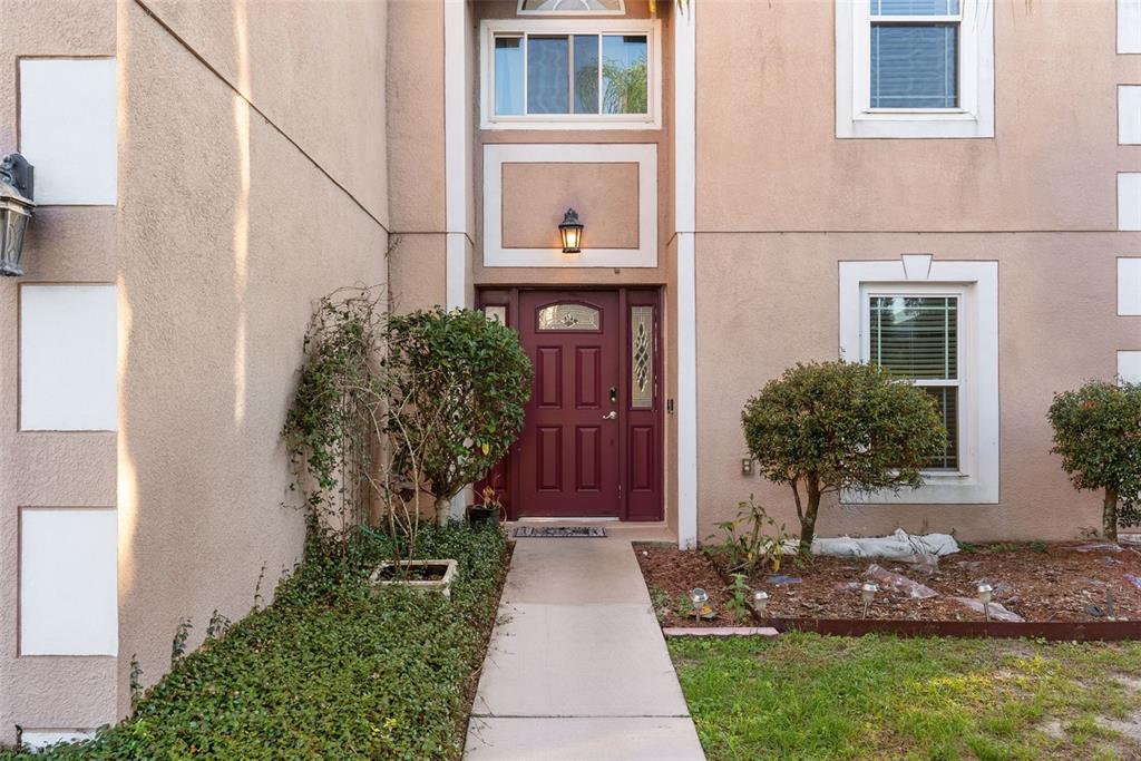 A concrete walkway leads to the front entrance of a two-story stucco home — 1009 RONLIN STREET, HAINES CITY, FL