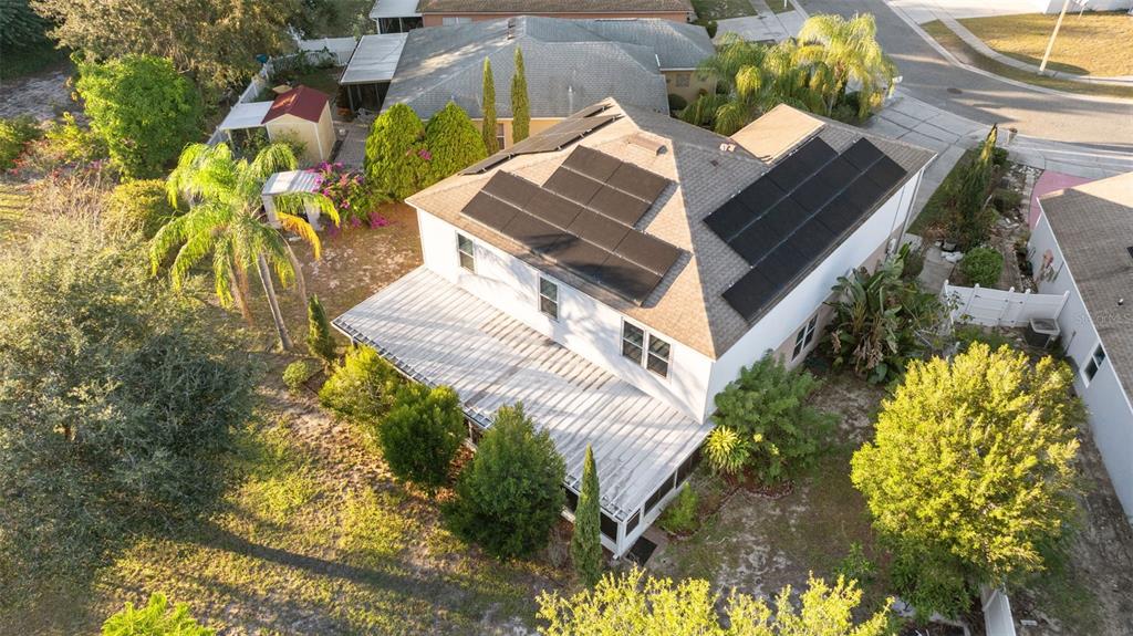 An aerial view shows a house with solar panels on the roof and a screened patio — 1009 RONLIN STREET, HAINES CITY, FL