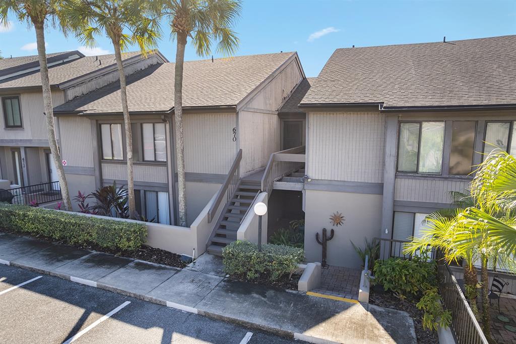 An exterior view of a multi-story residential building with stairs leading to an upper entrance — 670 LAKE VILLAS DRIVE UNIT C, ALTAMONTE SPRINGS, FL