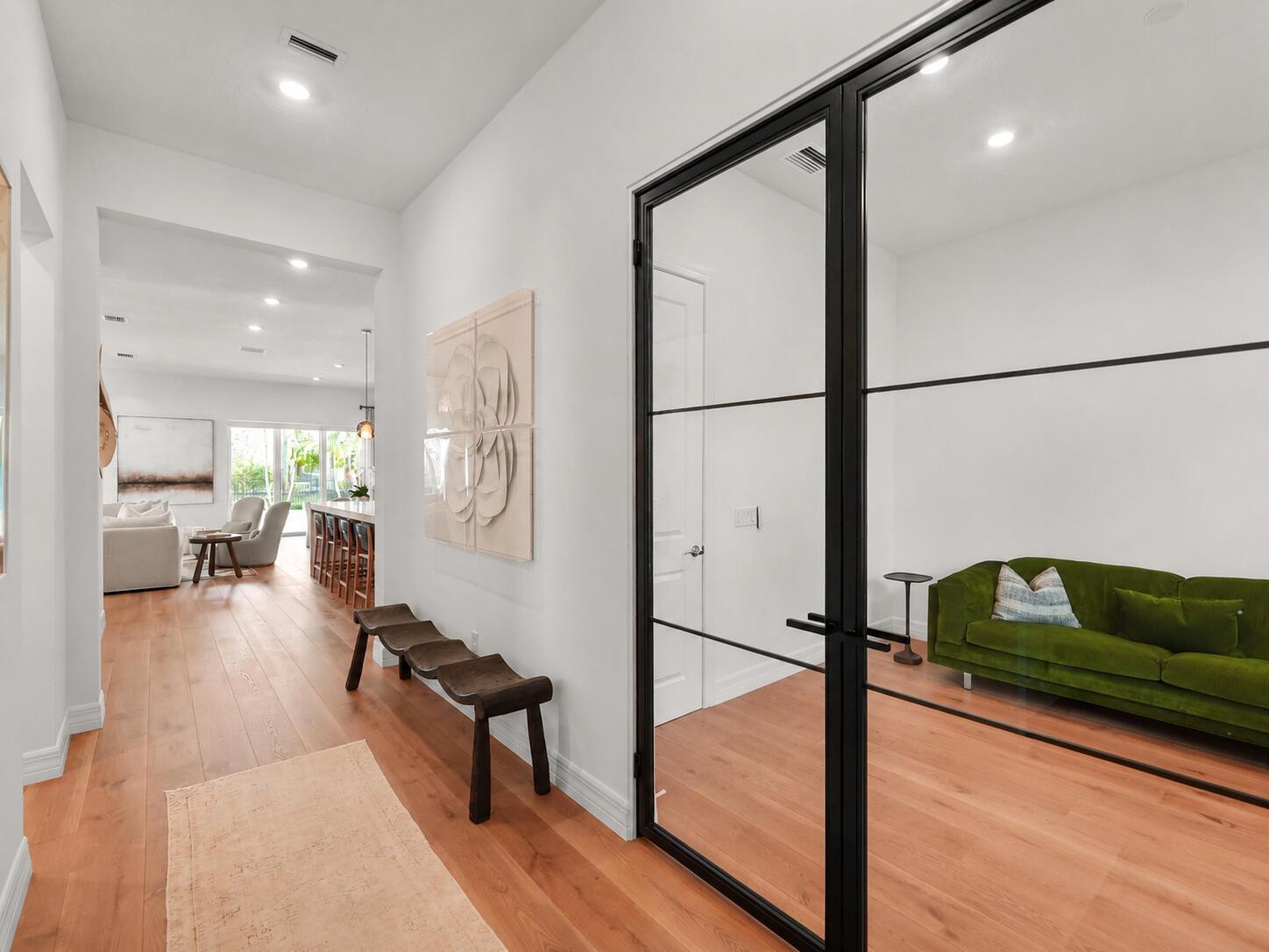 A modern kitchen features a large marble waterfall island, white cabinetry, and wood flooring — 10795 Stellar Circle, Palm Beach Gardens FL 33412, PALM BEACH GARDENS, FL