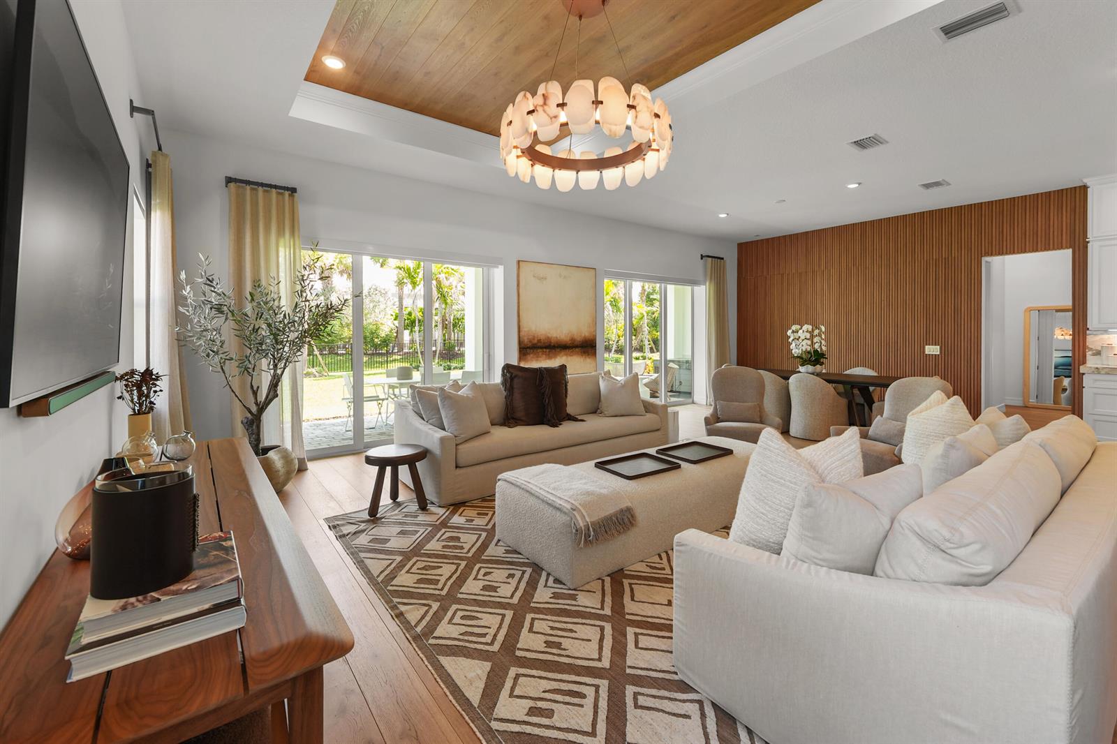 A modern kitchen features white cabinetry, marble countertops, a large waterfall island, and wood flooring — 10795 Stellar Circle, Palm Beach Gardens FL 33412, PALM BEACH GARDENS, FL